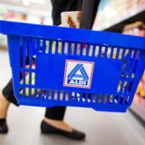 Eine Frau hält in einer Filiale von Aldi Nord einen blauen Einkaufskorb mit dem Logo.
