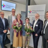 Vier Männer und zwei Frauen stehen vor dem Schild der Pflegeakademie Datteln.