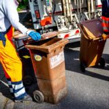 Arbeiter leeren Mülltonnen.