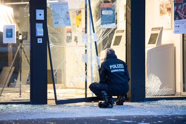 Eine Kriminaltechnikerin kniet vor der zerstörten Bankfiliale.