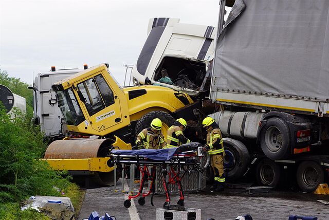 Das Bild zeigt die verkeilten LKW und Feuerwehrleute.