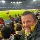 Ein Mann sitzt in einem Fußballstadion.