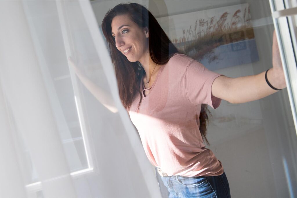 Eine Frau öffnet die Fenster, um zu lüften.