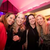 Vier Frauen schauen gut gelaunt in die Kamera.