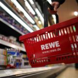 Ein Kunde geht in Köln in einem Rewe-Supermarkt mit einem Einkaufskorb am Kühlregal entlang.