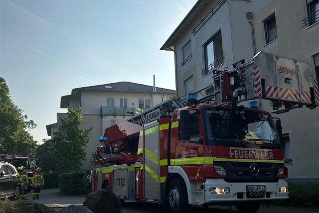 Ein Feuerwehrauto steht vor einem Wohnhaus.