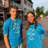 Ein Junge und ein Mädchen tragen dasselbe T-Shirt und blicken in die Kamera.