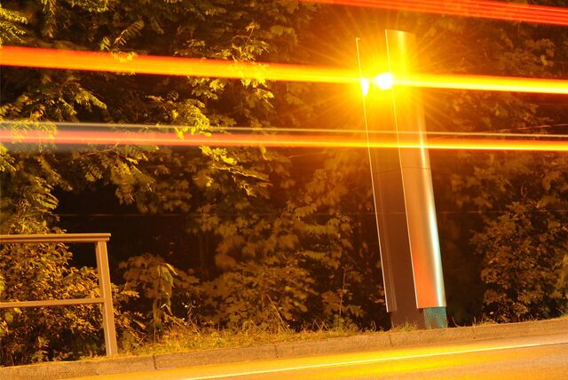 Ein Blitzgerät steht im Dunkeln am Straßenrand und löst aus.