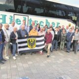 Eine Reisegruppe mit Fahne vor einem Reisebus.