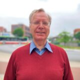 Porträt von Burkhard Becker. Im Hintergrund des Bildes sind die Hertener Höfe zu erkennen.