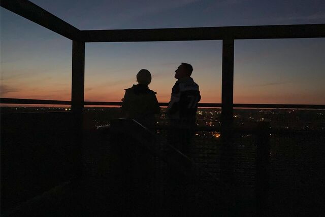 Ein Paar steht auf einer Aussichtsplattform auf der Halde Hoheward und schaut sich den Sonnenuntergang an.