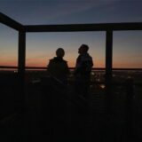 Ein Paar steht auf einer Aussichtsplattform auf der Halde Hoheward und schaut sich den Sonnenuntergang an.