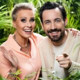 Sonja Zietlow und Jan Köppen, Moderatoren des Dschungelcamps, stehen zwischen mehreren Pflanzen.