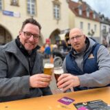 Zwei Männer stoßen mit einem Glas Bier an
