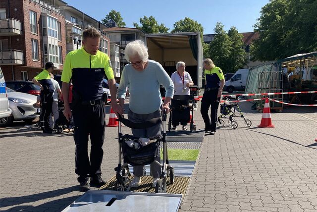 Polizist Karsten Quante hilft Rollator-Nutzerin Ruth Buß beim Überwinden von Hindernissen.