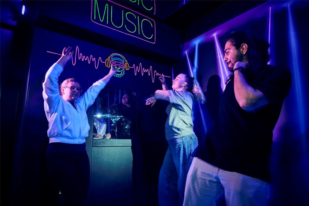 Junge Menschen tanzen in einem Raum zu Musik.