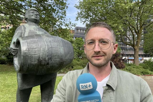 Die Skulptur „Bierkutscher“ trägt ein Fass Bier durch den Dortmunder Stadtgarten. Philipp Pohl steht davor.