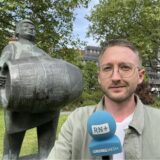 Die Skulptur „Bierkutscher“ trägt ein Fass Bier durch den Dortmunder Stadtgarten. Philipp Pohl steht davor.