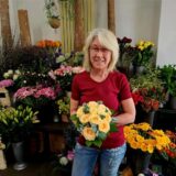 Floristin Christa Ziebur steht vor vielen Blumen.