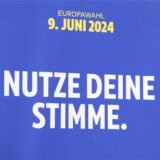 Ein Mann blickt auf dem Europafest in Frankfurt auf ein Plakat zur Europawahl 2024 mit der Aufschrift „Nutze Deine Stimme“.