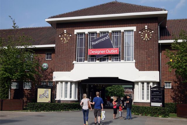 Menschen stehen vor dem Eingang des Designer Outlets in Roermond (Niederlande).