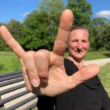 Yvonne Hartig zeigt die Solidaritätsgebärde: Sie hat die Hand ausgestreckt, Ring- und Mittelfinger sind abgeknickt, alle anderen Finger gespreizt.