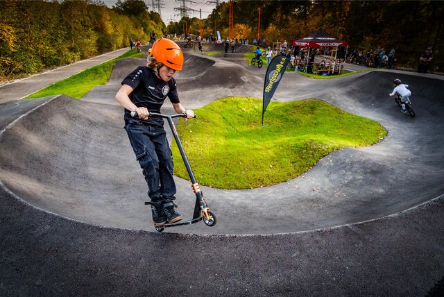 Ein junger Rollerfahrer ist auf einem Pumptrack unterwegs.