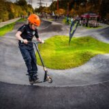 Ein junger Rollerfahrer ist auf einem Pumptrack unterwegs.
