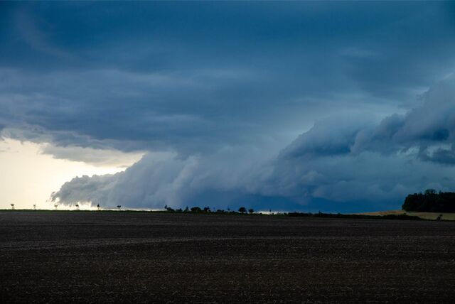 Dunkle Wolken ziehen über ein Feld.