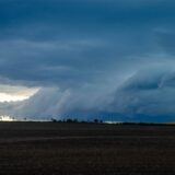 Dunkle Wolken ziehen über ein Feld.