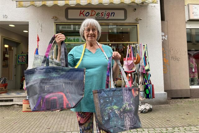 Kornelia Helisch zeigt vor ihrem Geschäft KoDesign am Holzmarkt in Recklinghausen einige restliche Exemplare von Einkaufstaschen, die aus einer Baustellenplane genäht sind, die etwa vier Jahre am Stadthaus E gehangen hatte.