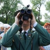 Ein Mann in Schützenuniform schaut durch ein Fernglas.