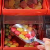 Eine Kinderhand nimmt Bonbons aus einer Verkaufsbox.