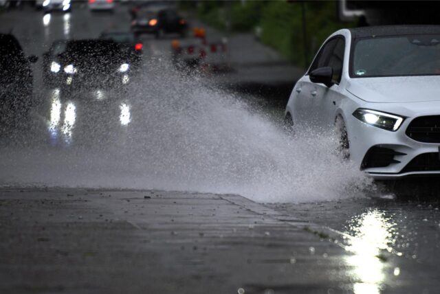 Ein Auto fährt durch eine große Wasserlache.