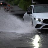 Ein Auto fährt durch eine große Wasserlache.