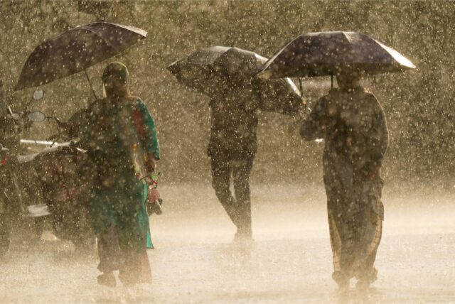 Menschen laufen während eines plötzlichen Regenschauers mit Regenschirmen in der Hand.