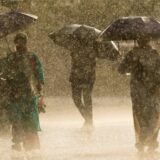 Menschen laufen während eines plötzlichen Regenschauers mit Regenschirmen in der Hand.