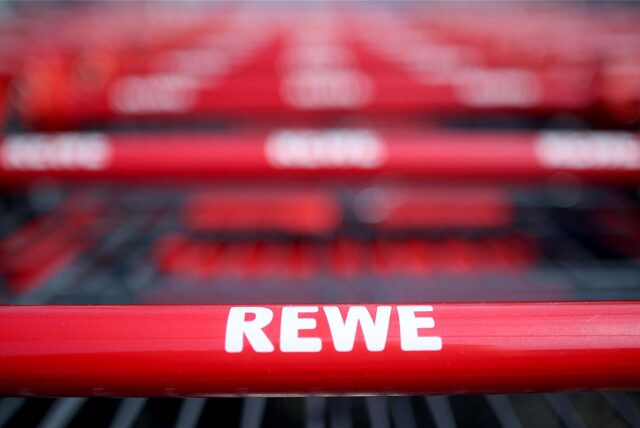Einkaufswagen stehen vor einem Rewe-Supermarkt.