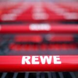 Einkaufswagen stehen vor einem Rewe-Supermarkt.