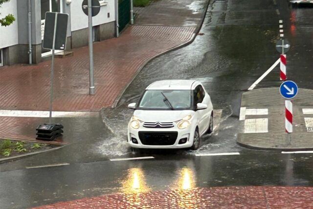 Ein Auto fährt durch eine tiefe Pfütze.