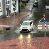 Ein Auto fährt durch eine tiefe Pfütze.