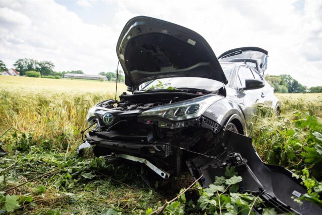 Ein Autowrack steht auf einem Feld.