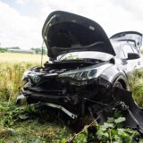 Ein Autowrack steht auf einem Feld.