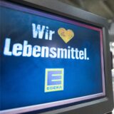 Eine Kundin räumt in einem Edeka-Markt an der Kasse ihren Einkauf auf das Laufband.
