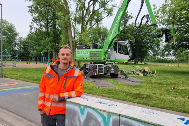 Ein Mann steht vor einem Bagger.