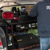 Ein Ordnungsamts-Mitarbeiter steht hinter einem Radarwagen der Stadt.