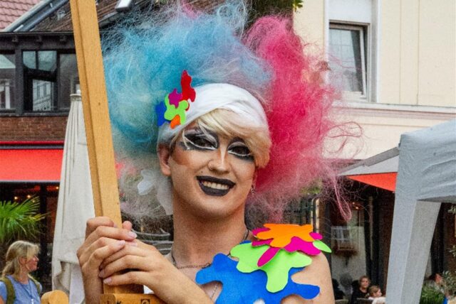 Queerer Mensch bunt gekleidet auf dem Markt