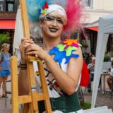 Queerer Mensch bunt gekleidet auf dem Markt