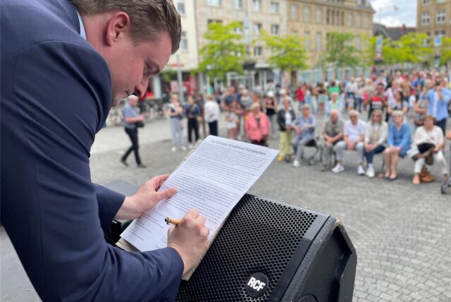 Das Brandmauer-Versprechen in der Castroper Altstadt am 26. Mai 2024: MdB Michael Breilmann (CDU) unterzeichnet das überparteiliche Dokument für die Ratsfraktion.