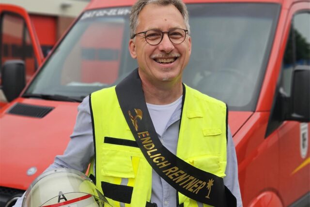 Ein Mann steht vor einem Feuerwehrwagen.